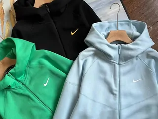Zip hoodies in green and pale blue on a hanger
