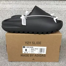 A black foam slide standing on a brown shoebox with a size label