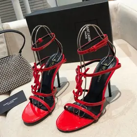 Red patent strappy high-heeled sandals on a sofa
