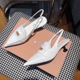 White pointed slingback shoes on a pink box and houndstooth cloth
