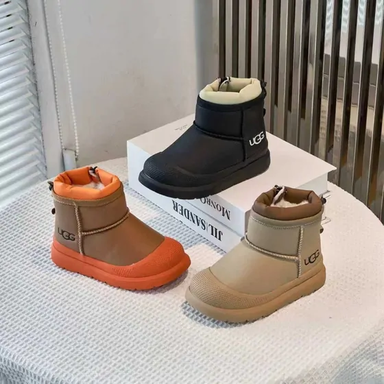 Three short boots in orange, black and taupe on a table